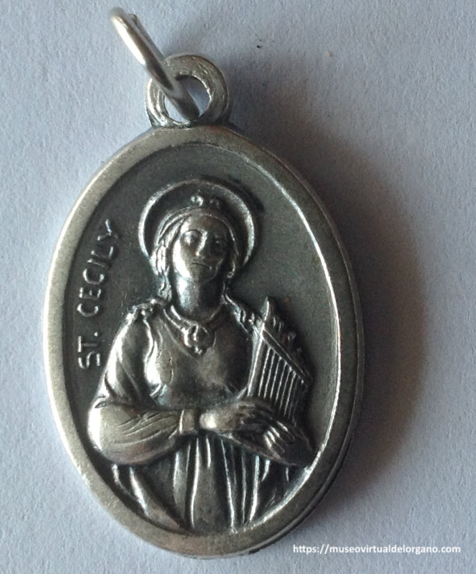 Medalla devocional de Santa Cecilia (St. Cecily). Italia, ca. 1950-1965, en aleación de aluminio. Anverso: imagen de Santa Cecilia sosteniendo un órgano y la inscripción «ST. CECILY».